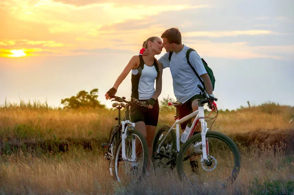 快乐的年轻夫妇爱自行车反对日落背景 — 图库照片