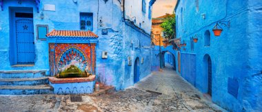 Colorful fountain with drinking water on house wall in famous blue town of Chefchaouen. Morocco, North Africa clipart