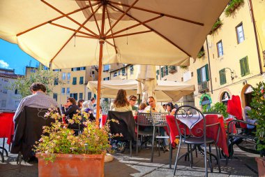 LUCCA, İtalya - 12 Ekim 2013: Kentin tarihi merkezindeki Piazza Anfiteatro 'daki açık hava kafesi. İnsanlar güneş şemsiyeleri altında dinleniyor. Toskana