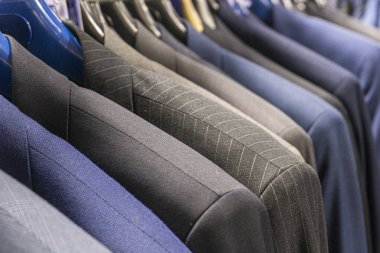 Bir erkek giyim mağazasında mavi ve gri ceketler.