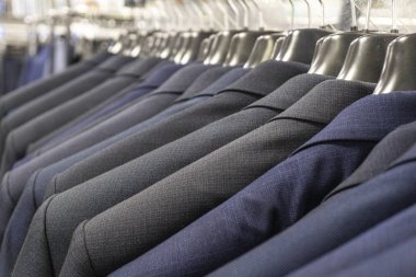 Bir erkek giyim mağazasında mavi ve gri ceketler.