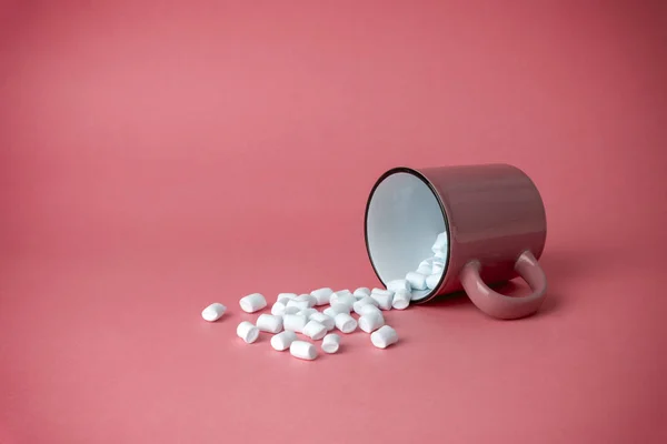 Overturned cup with marshmallows on a pink background. Cocoa dri — Stock Photo, Image