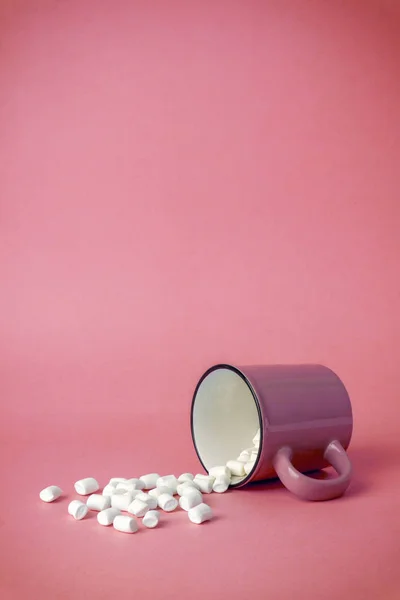 Overturned cup with marshmallows on a pink background. Cocoa dri — Stock Photo, Image