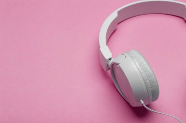 Renkli pembe arka planda müzik kulaklıkları. Estetik yeniden canlandırma
