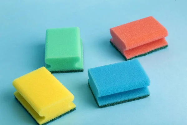 Esponjas de colores para lavar los platos sobre un fondo azul — Foto de Stock