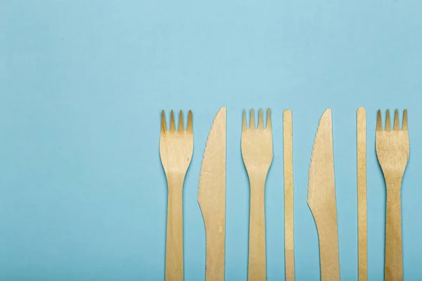 Tenedores de madera y cuchillos para la comida en una taza de papel en un bac de color — Foto de Stock