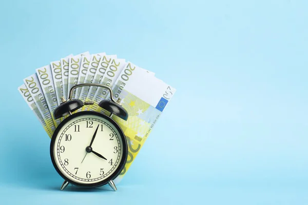 Zaman ve para kavramı. Mavi sırtlı Euro nakit ve çalar saat — Stok fotoğraf