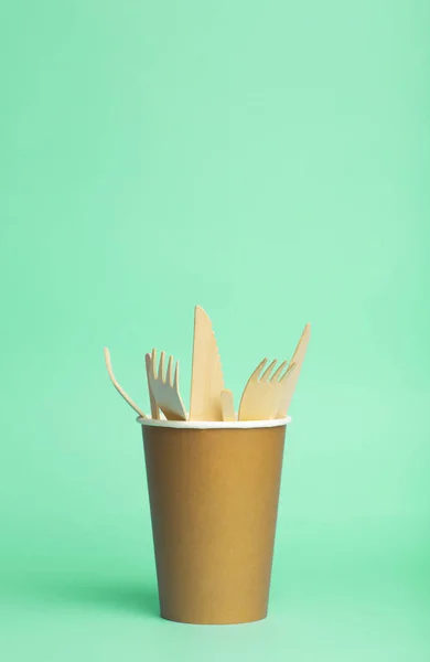 Tenedores de madera, cuchillos y cucharas para la comida en una taza de papel sobre un col — Foto de Stock