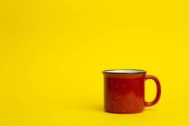 Sarı arka planda kırmızı seramik bardak. Eski ve eski bir bardak.