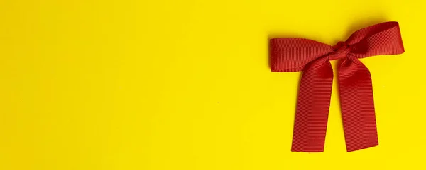 Gift bow on a yellow banner background. Red gift bow with shadow