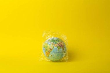 Plastik torba kirliliği. Dünya küresi plastik bir torba içinde