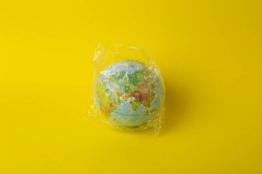 Plastik torba kirliliği. Dünya küresi plastik bir torba içinde