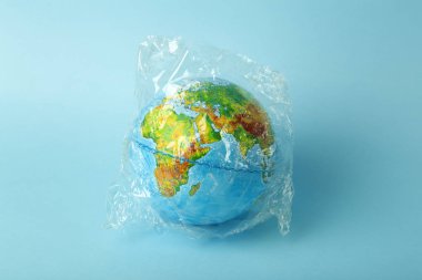Plastik torba kirliliği. Dünya küresi plastik bir torba içinde
