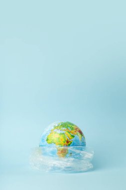 Plastik torba kirliliği. Dünya küresi plastik bir torba içinde