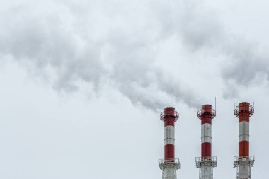 Hava kirliliği konsepti. Gri gökyüzünün arka planındaki borulardan çıkan fabrika dumanı.