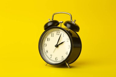 Zaman arkaplanı kavramı. Sarı boş arkaplanda klasik alarmlı saat. Zaman yönetimi kavramı.