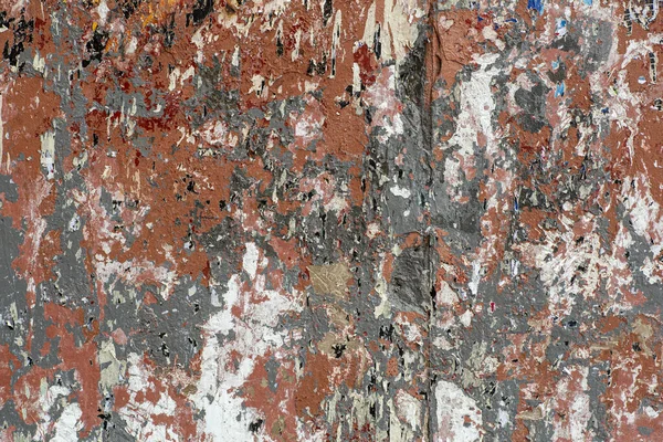 Wall with traces of old peeling paint, torn paper and glue background. Texture of a dirty street wall with torn ads and posters.