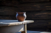 Tontopf (Tonkeramik) auf einem alten Holztisch in einem alten rustikalen Haus. Töpferei und bäuerliches Leben. Stillleben mit Keramik.