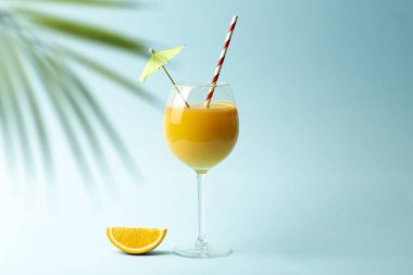 Yaz içkileri konsepti. Renkli mavi arka planda cam bir fincanda portakal suyu. Tropikal yaz arka planı.