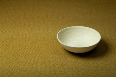 Arka planda halı var. Aynı renkte sarı bir halı ve ahşap bir kase. İç tasarım ve üretim.