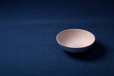 Arka planda halı var. Aynı renkte mavi bir halı ve ahşap bir kase. İç tasarım ve üretim.