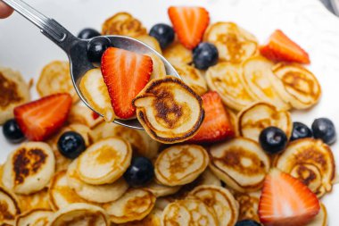 Kahvaltıda minik gözlemeler. Sabah kahvaltıda ev mutfağında çilekli krep ve yaban mersini pişirilir. Yiyecek Arkaplanı.