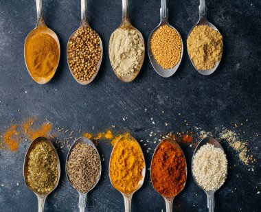 Kaşıklar arka planda baharatlar. Yemek pişirmek için çeşitli baharatlar (zerdeçal, biber, biber, kişniş, tarçın) ve biberler. Mutfak yemekleri konsepti.