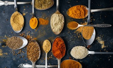 Kaşıklar arka planda baharatlar. Yemek pişirmek için çeşitli baharatlar (zerdeçal, biber, biber, kişniş, tarçın) ve biberler. Mutfak yemekleri konsepti.