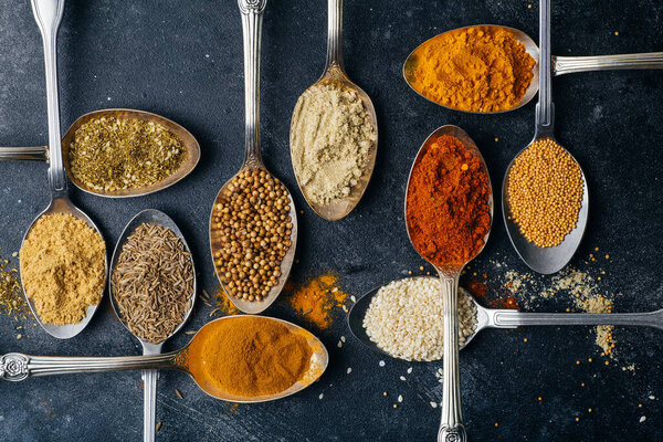 Spices in spoons background. Varieties of spices (turmeric, pepper, chili, coriander, cinnamon) and peppers for cooking. Culinary food concept.