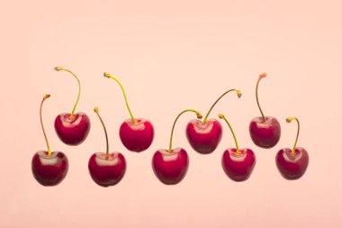 Kiraz arkaplanı çok az. Pembe, boş mavi arka planda kırmızı yaz kiraz üzümleri. Yaz meyveleri ve gıda konsepti.