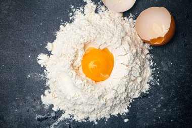 Hamur Tarifi. Pizza, makarna ve fırın için hamur malzemeleri. Koyu arkaplanda un, yumurta ve sebze yağı var..