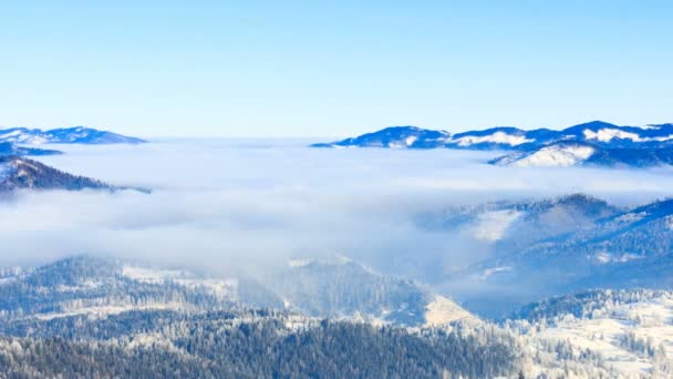 Paisaje de invierno. Niebla moviéndose sobre la montaña en invierno con un cielo azul — Vídeos de Stock