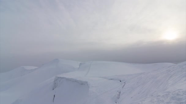 Time lapse of clouds running on blue sky over amazing white landscape of high rocky mountains and snowy valley — Stock Video