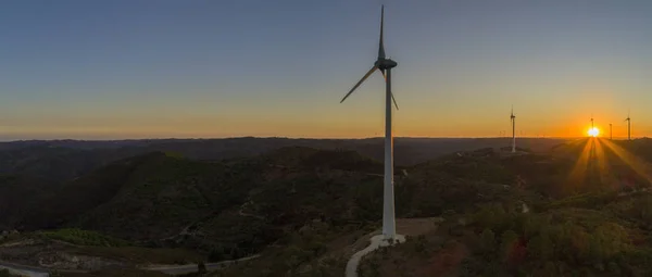 Aerial Wind farm turbines silhouette at sunset. Clean renewable energy power generating windmills. Algarve countryside. .
