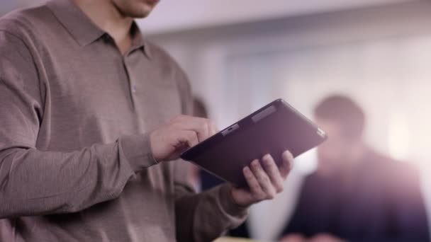 Giovane uomo sta digitando su un tablet in ufficio mentre gruppo di lavoro — Video Stock