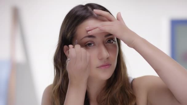 Young attractive woman plucks her eyebrows — Stock Video