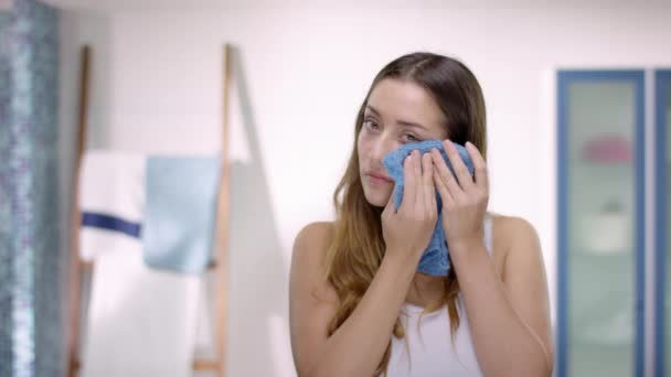 Mujer atractiva joven se lava la cara con una toalla facial — Vídeos de Stock