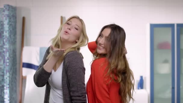 Dos mujeres hermosas jóvenes haciendo poses con mucha diversión delante de un espejo — Vídeos de Stock