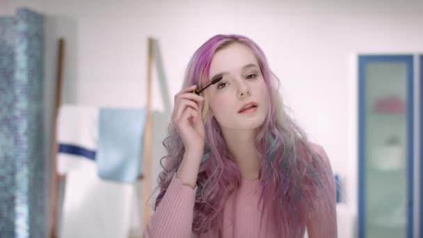 Молода жінка в статевому дозріванні з рожевим волоссям намагається туш на її віях — стокове відео