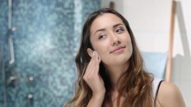 Молодая женщина удаляет макияж с помощью тампона — стоковое видео