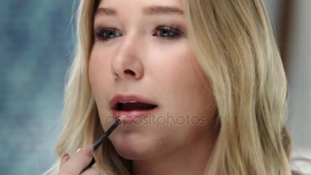 Young caucasian woman is applying  lip gloss on her lips — Stock Video