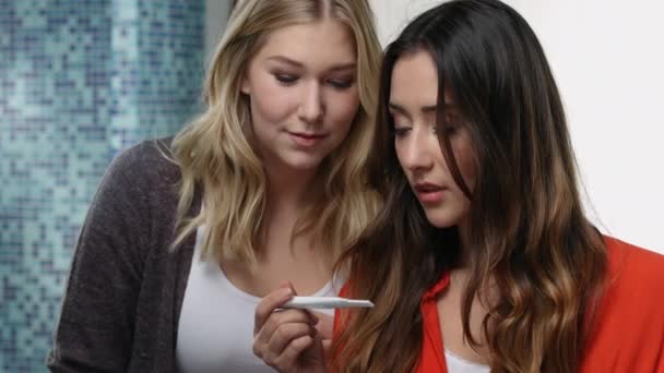 Два друга празднуют результаты теста на беременность в ванной комнате — стоковое видео