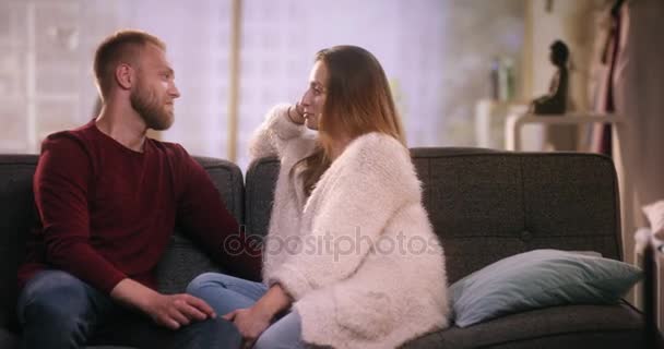 陽気なカップルの話と笑いのソファに座って — ストック動画