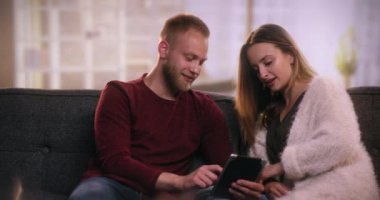 Tablet kullanarak koltukta oturan genç çekici çift