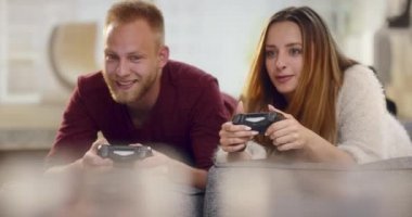 Genç çift kanepe holding uzaktan kumanda üzerinde yalan ve video oyunları oynarken