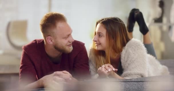 Jonge natuurlijke paar verliefd liggend op de Bank en lachen — Stockvideo