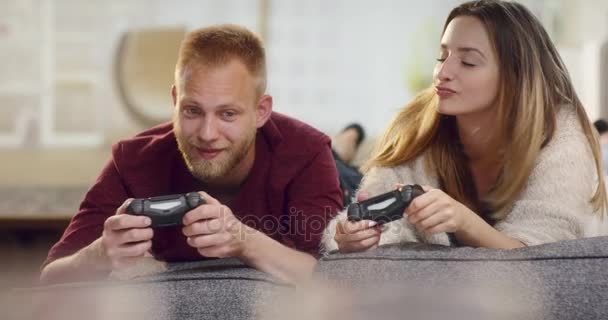 遊び心のあるかわいいカップル ビデオ ゲームをプレイしながらソファから落ちる — ストック動画