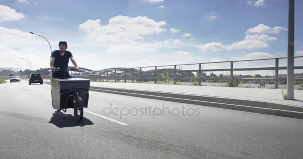 Красивый человек на черном грузовом велосипеде вдоль реки Эльба — стоковое видео