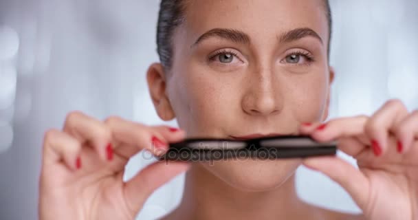 Pretty woman is showing a mascara while she looks into the camera — Stock Video