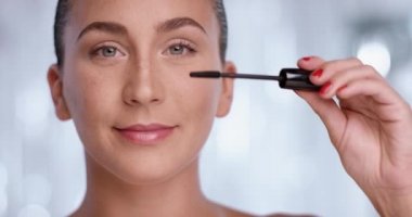 Çekici kadın onun güzel gözleri için kameraya doğru bakarken maskara kullanıyor